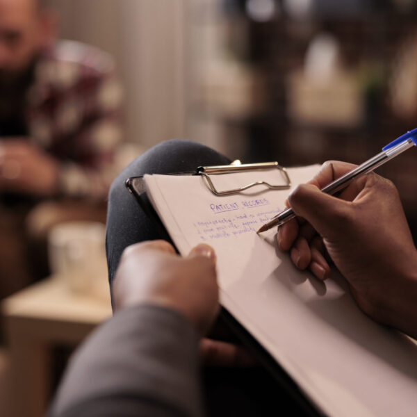 Male psychologist taking notes at couple therapy session to help with relationship issues, counselor giving advice. Explaining marriage problems, using paper to do psychoanalysis. Close up,